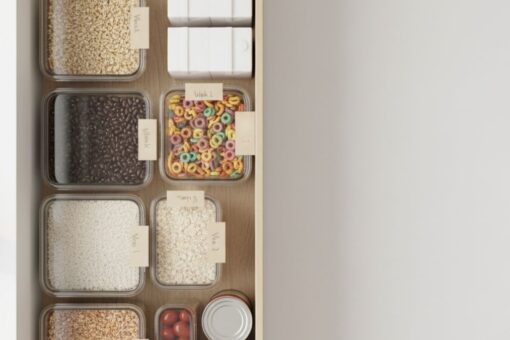 Neatly organized pantry shelf with clear containers of staples and simple week labels in soft morning light.